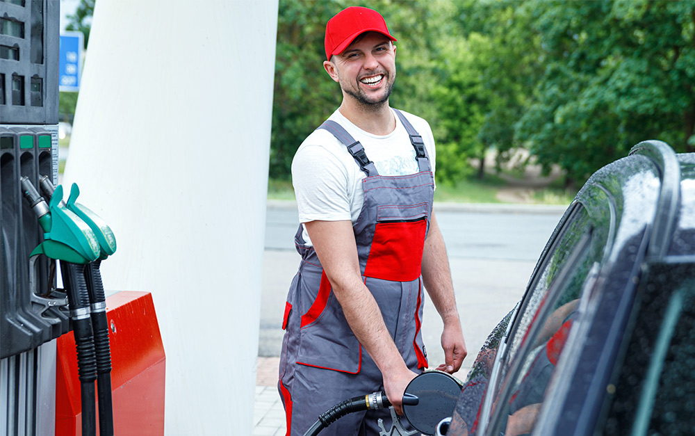 Imagem de um frentista realizando o atendimento em um posto de combustíveis.